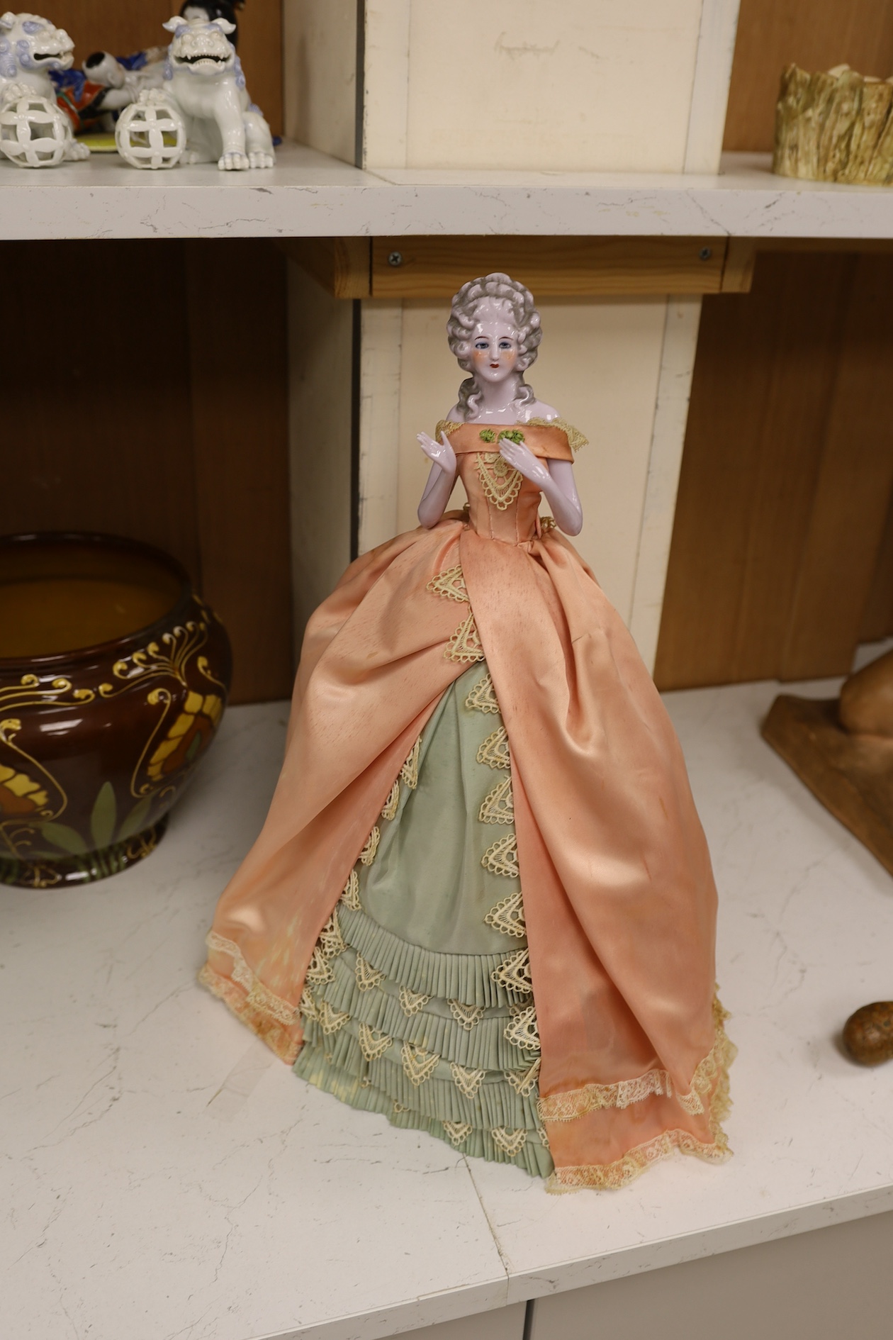 A 1920’s German porcelain 'pin dolly' with tea cosy dress, 46cm high. Condition - good some marks to the silk of cosy/dress